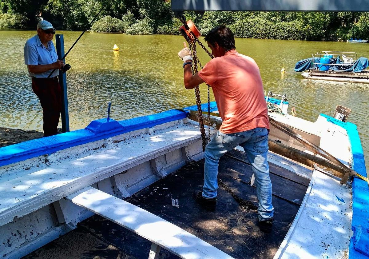 Imagen secundaria 1 - Labores de rehabilitación de la barca antes de ser devuelta al agua ayer (deabjo a la izquierda). A la derecha, la barca ya amarrada en el río.