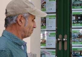 Un hombre pasea junto al escaparate de una inmobiliaria donde se anuncian viviendas en alquiler.