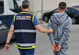 Un agente de la Policía Nacional conduce a comisaría a uno de los detenidos en la operación contra una banda de atracadores.