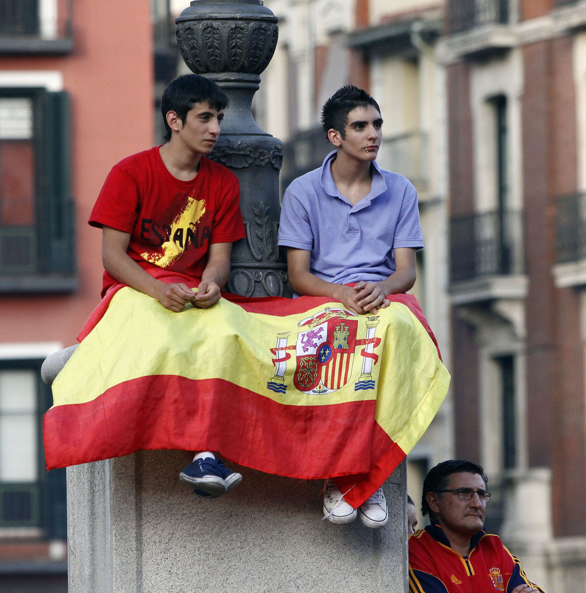 Dos jóvenes encaramados a una farola de la Plaza Mayor de Valladolid.