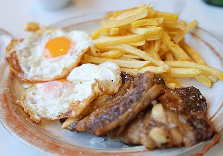 Segundo plato del menú, churrasco de ternera con dos huevos y patatas.