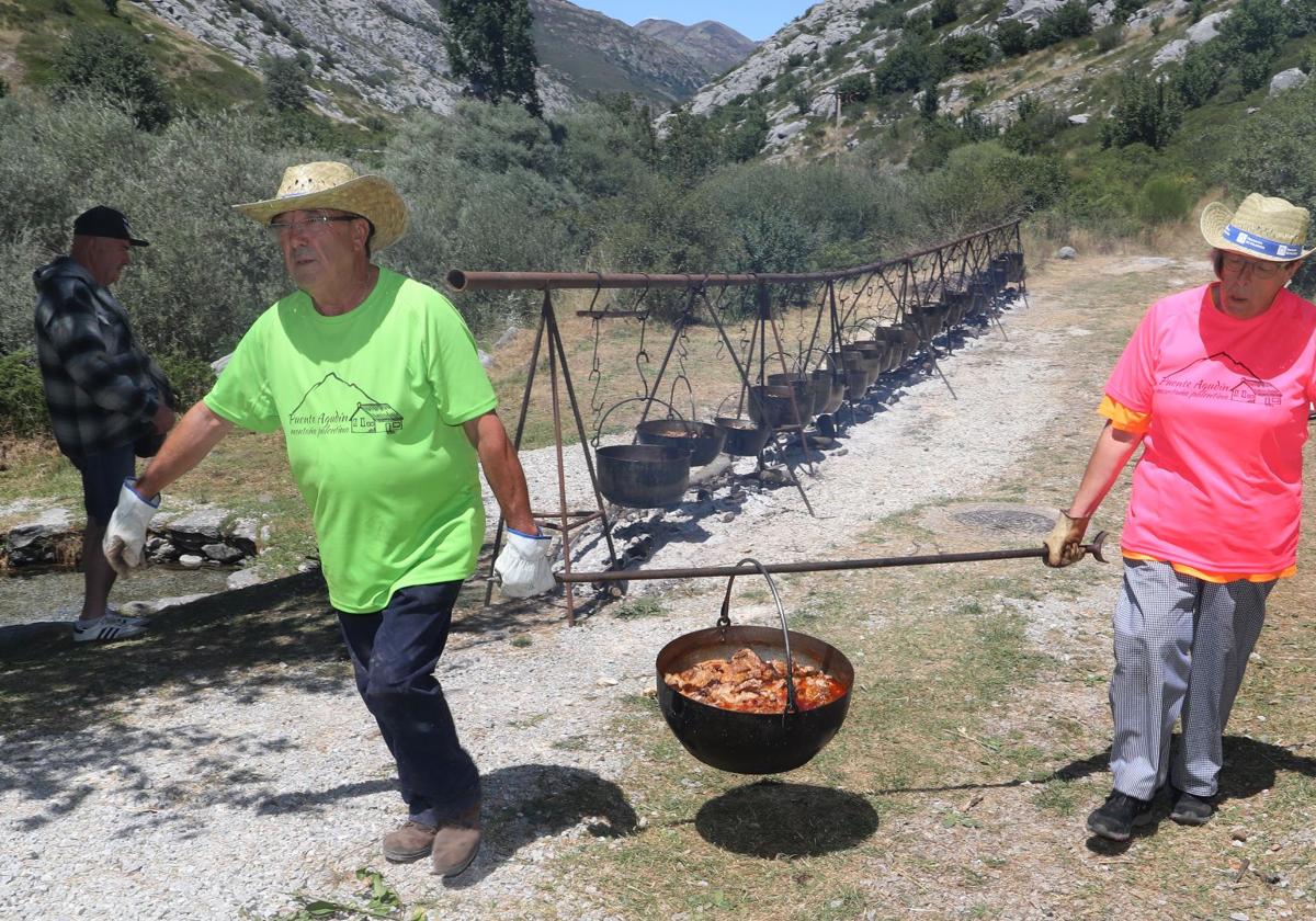Una de las calderetas es retirada del fuego para servirla entre los asistentes.