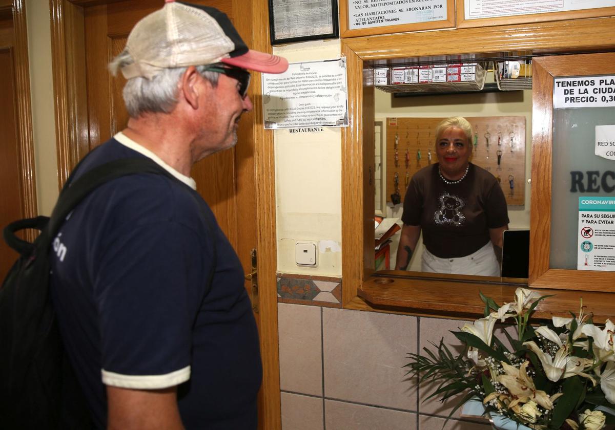 El demandante de ayuda a Cáritas consulta el precio de una habitación en un hostal.
