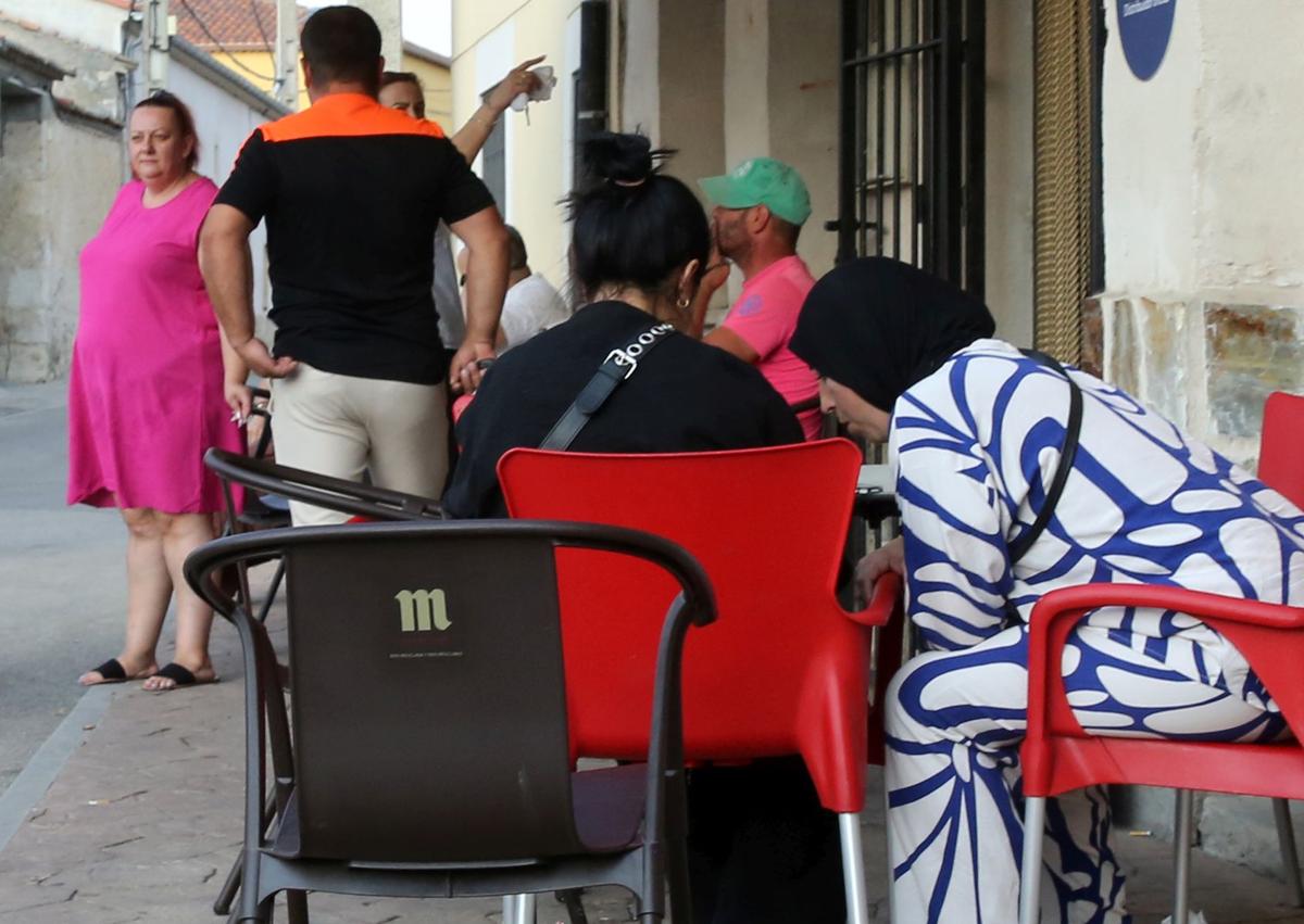 Imagen secundaria 1 - Arriba, dos mujeres, una española y otra extranjera, se abrazane n la terraza de un bar. Abajo algunos vecinos magrebíes charlan a las afueras del local, y a la izquierda, dos vecinos comparten una cerveza después del trabajo.