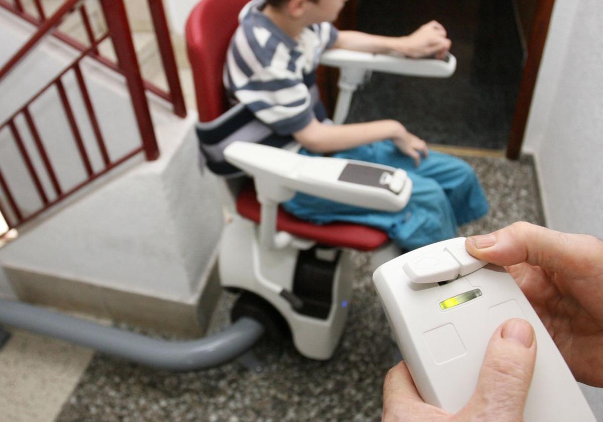 Un niño con parálisis cerebral, en una imagen de archivo, sube un tramo de escalera con un mecanismo adaptado.