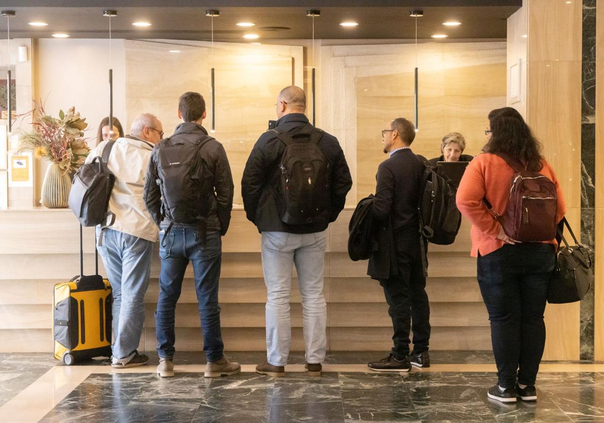 Clientes de un hotel vallisoletano cumplimentando gestiones en la recepción del establecimiento.