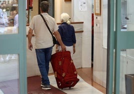 Dos turistas se dirigen con su equipaje a la recepción de un céntrico hotel de Segovia.