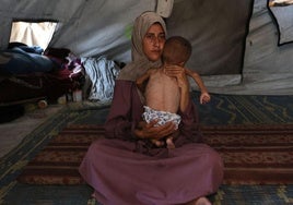 Una madre palestina acuna a su hijo enfermo que muestra signos de desnutrición.