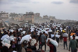 Palestinos transportan suministros después de que los camiones de ayuda entraran en la Franja de Gaza.