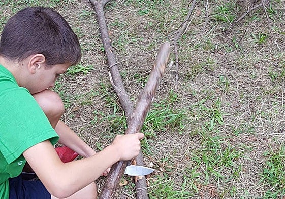 Un niño aprendiendo a hacer fuego en el campamento de verano.