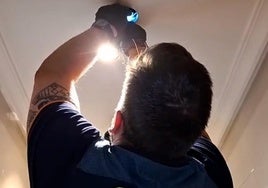 Un agente de la Guardia Civil retira la cámara que el detenido tenía escondida en un foco del techo de su baño y con la que grababa a familiares y amigos sin su consentimiento.