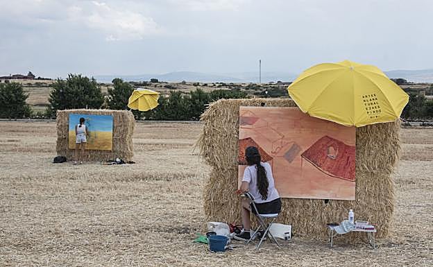 Dos pintoras realizan sus creaciones sobre los lienzos de pacas de paja.
