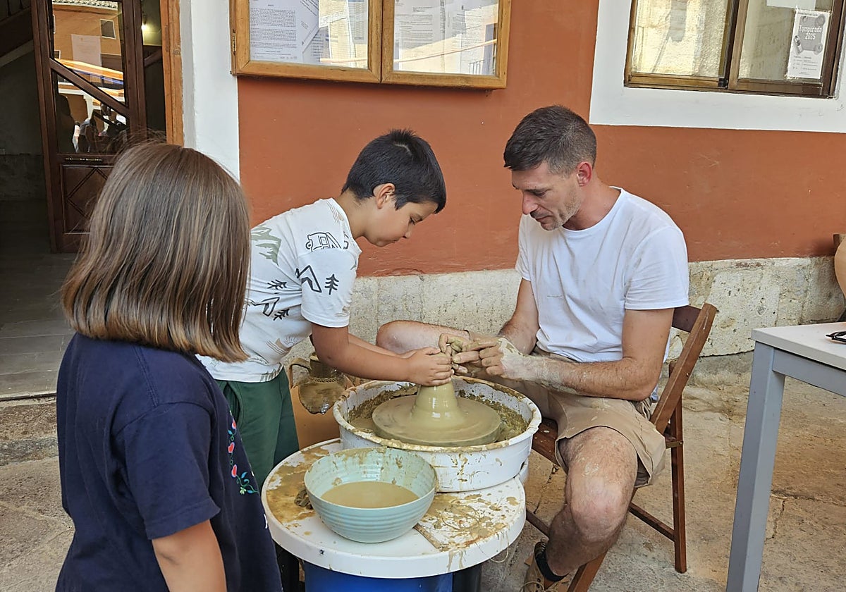 El alfarero tiedrano Israel Álvarez Gato guía a un niño en la realización de una minicántaro de la novia