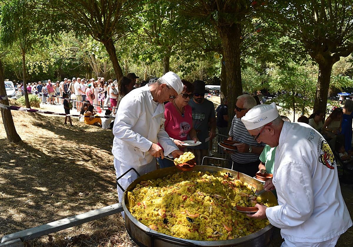 Los cocineros sirven raciones de paella a los asistentes, que forman una larga cola.