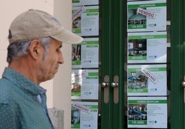 Un hombre pasa junto a los anuncios de un escaparate de una inmobiliaria en Segovia.
