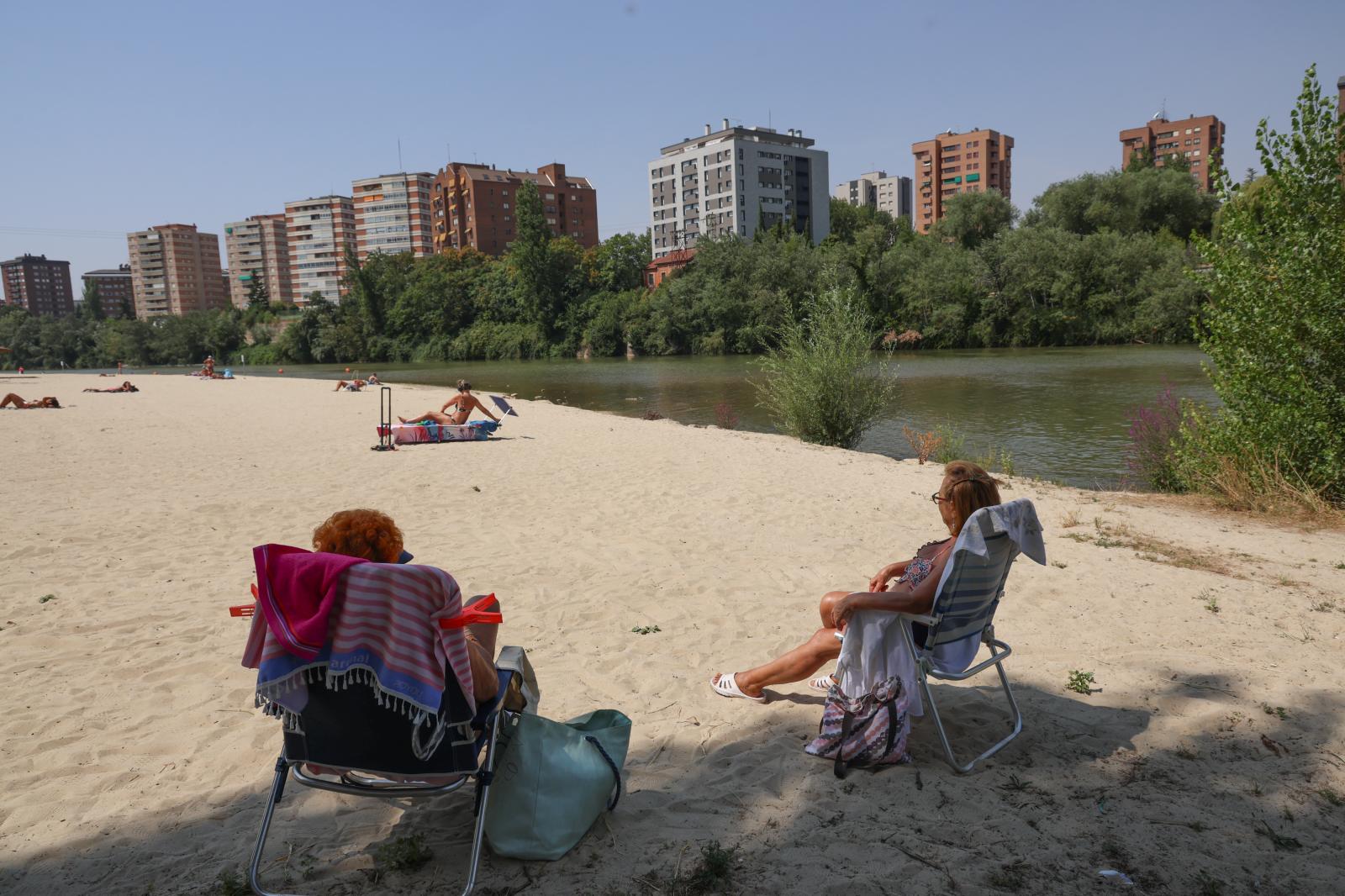 Dos amigas sentadas a la sombra en la playa fluvial de Las Moreras.