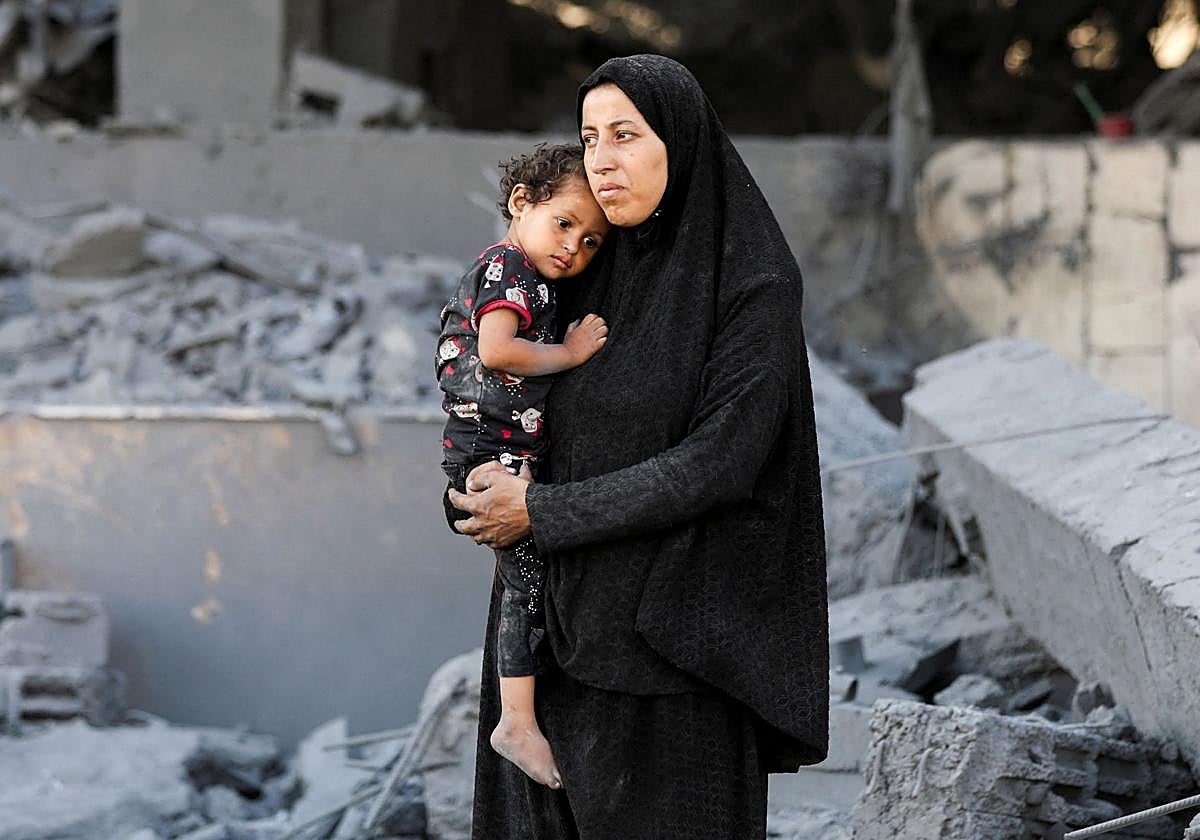 Una mujer palestina sostiene a un niño en las inmediaciones de una clínica evacuada de la UNRWA, tras un ataque israelí.