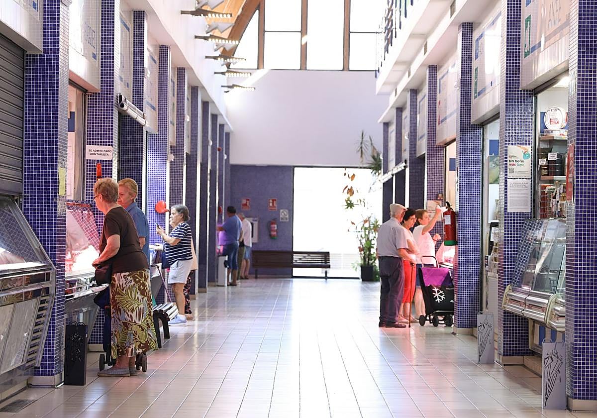 Clientes haciendo la compra en los pocos puestos de autónomos que continúan abiertos en el Mercado de Delicias de Valladolid.