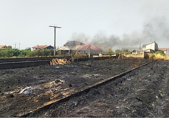 Al fondo, una nave arde en Cubo de Benavente, población a la que han llegado las llamas