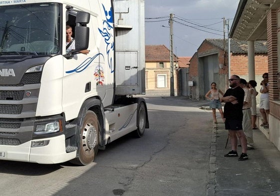 Un camión pasa junto a varios vecinos delante de una vivienda de Chañe.