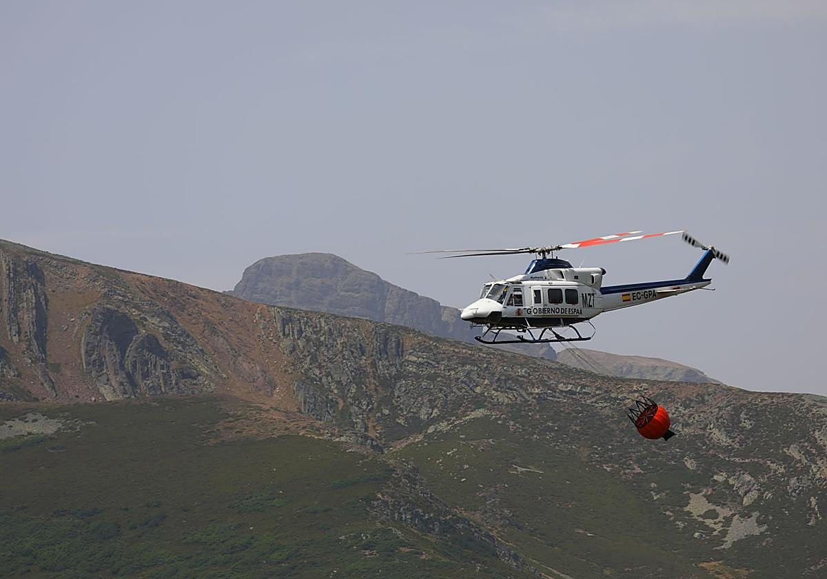 Un helicóptero del Gobierno lleva agua para extinguir el fuego, en la zona de Peña Carazo.
