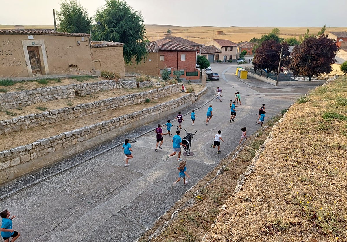 Niños y jóvenes corren delante del carretón en una recreación lúdica de la vaca enmaromada