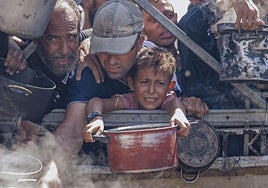 Un niño trata de conseguir comida en los centros de distribución de ayuda humanitaria en Gaza.