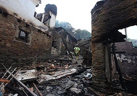 Bomberos apagan los rescoldos de casas incendiadas en la localidad leonesa de Lusio.