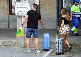 Turistas esperan con maletas a las puertas de un hotel en Segovia este domingo.