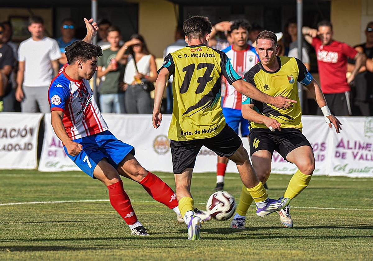 El rojiblanco Jorge golpea a portería presionado por Adrián y Fran, del Mojados.
