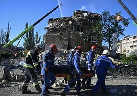 Rescatistas trasladan a una de las víctimas entre los escombros de uno de los edificios golpeados ayer por Rusia en Kiev.