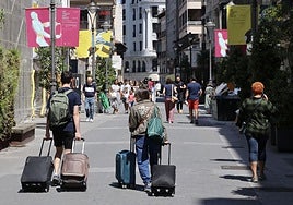 Viajeros con maletas por la calle Santiago, este mes de agosto.