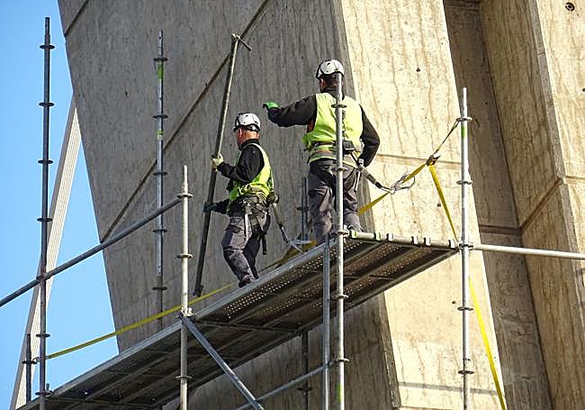 Los operarios retiran la estructura metálica del andamio que cubría la vela del puente.