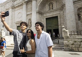 Tres personas se fotografían ante la entrada principal de la Catedral de Valladolid.