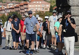 Turistas se protegen del sol con gafas y viseras en su visita a Segovia.