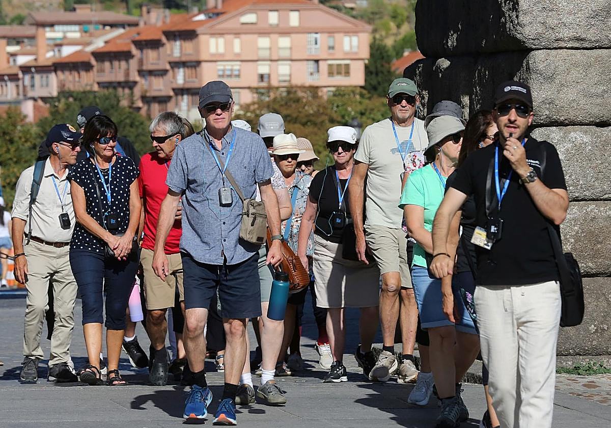 Turistas se protegen del sol con gafas y viseras en su visita a Segovia.