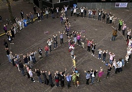 Imagen de archivo de personas realizando un gran símbolo de la paz.