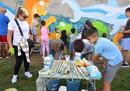 Los participantes cogen pinceles y pintura para colorear el mural.