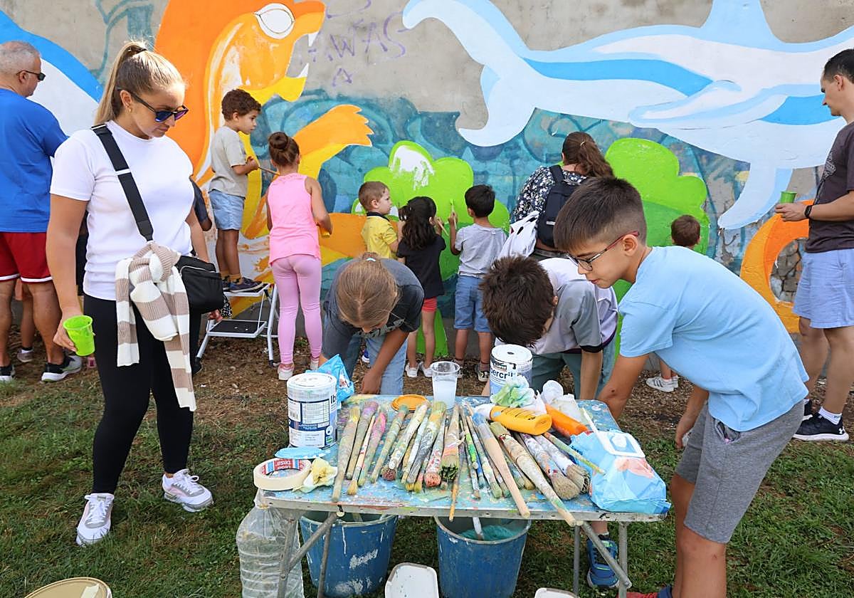 Los participantes cogen pinceles y pintura para colorear el mural.