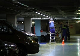 Operarios trabajan en la instalación del sistema de guiado de plazas libres y ocupadas en el primer sótano del aparcamiento.