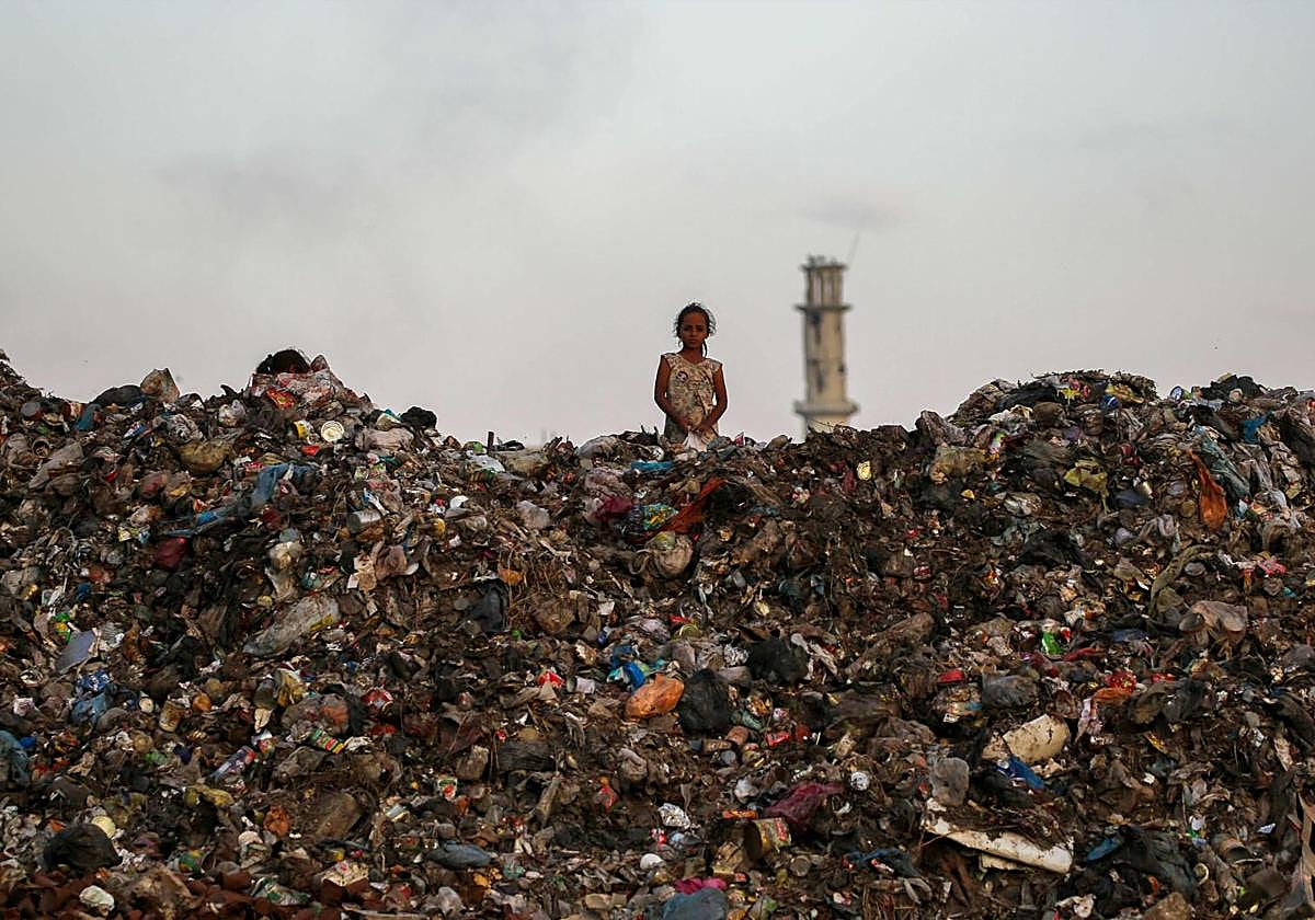 Una niña entre una montaña de escombros y basura en Gaza.