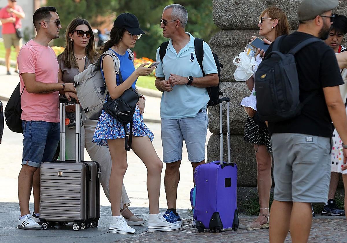 Un grupo de personas espera con maletas a los pies del Acueducto.