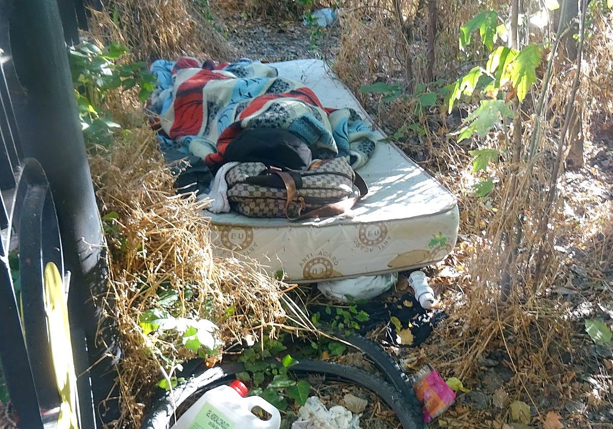 Un indigente duerme en un colchón, rodeado de basura, en la ribera del río frente al albergue municipal del paseo de Extremadura.