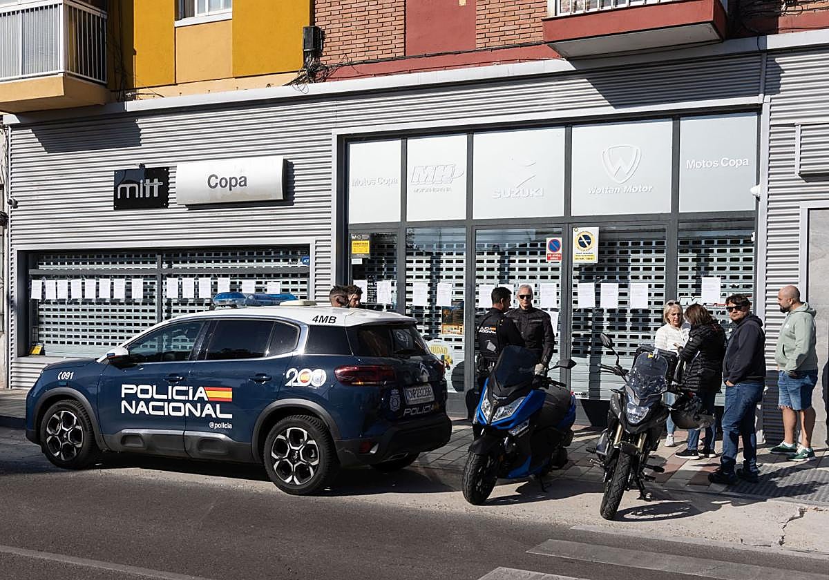 Agentes de la Policía Nacional y afectados por el cierre de Motos Copa en Valladolid delante de la tienda esta mañana.