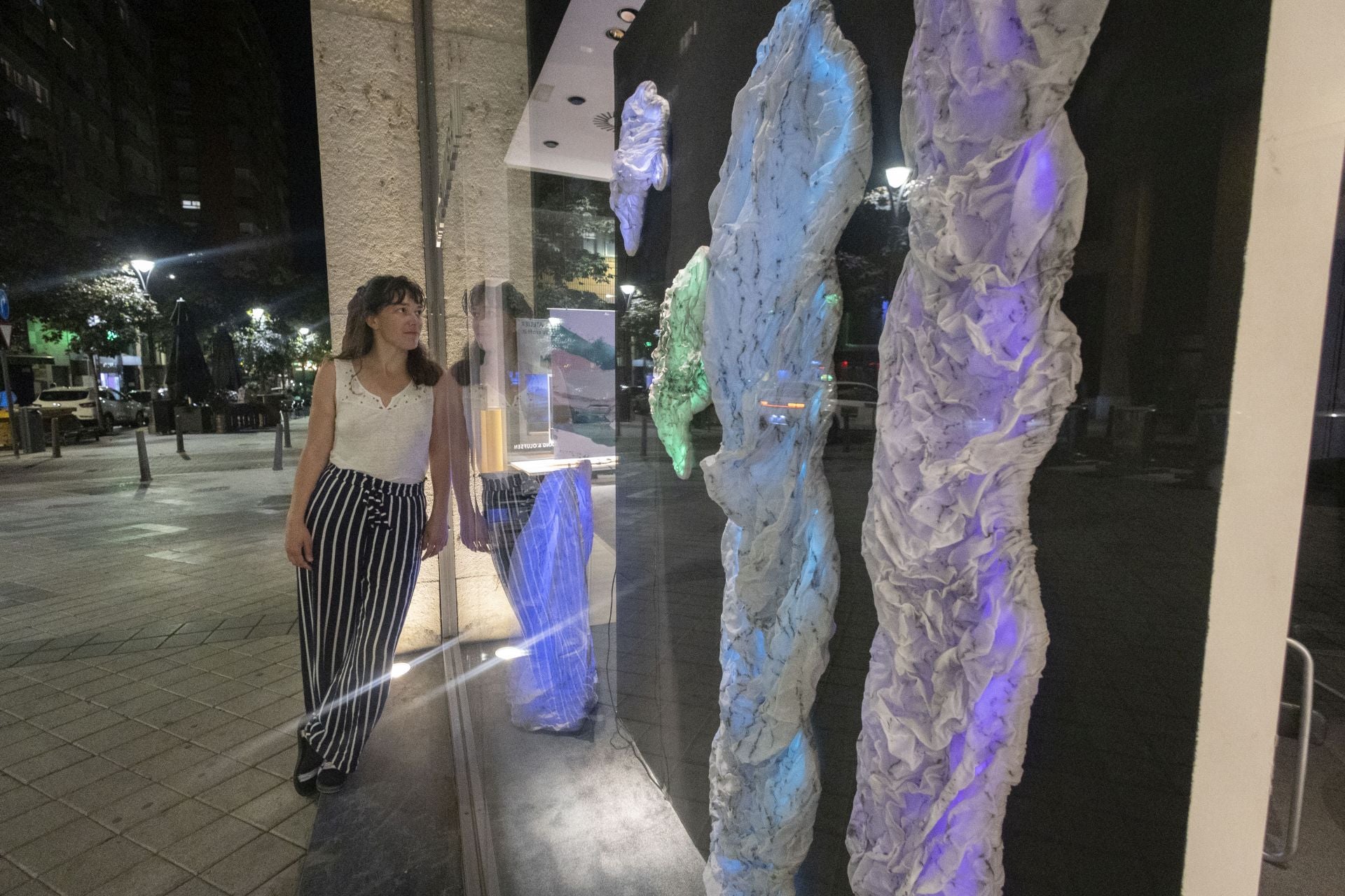 Ruta Simutyte con su instalación en el escaparate de una tienda en la calle San Lorenzo.