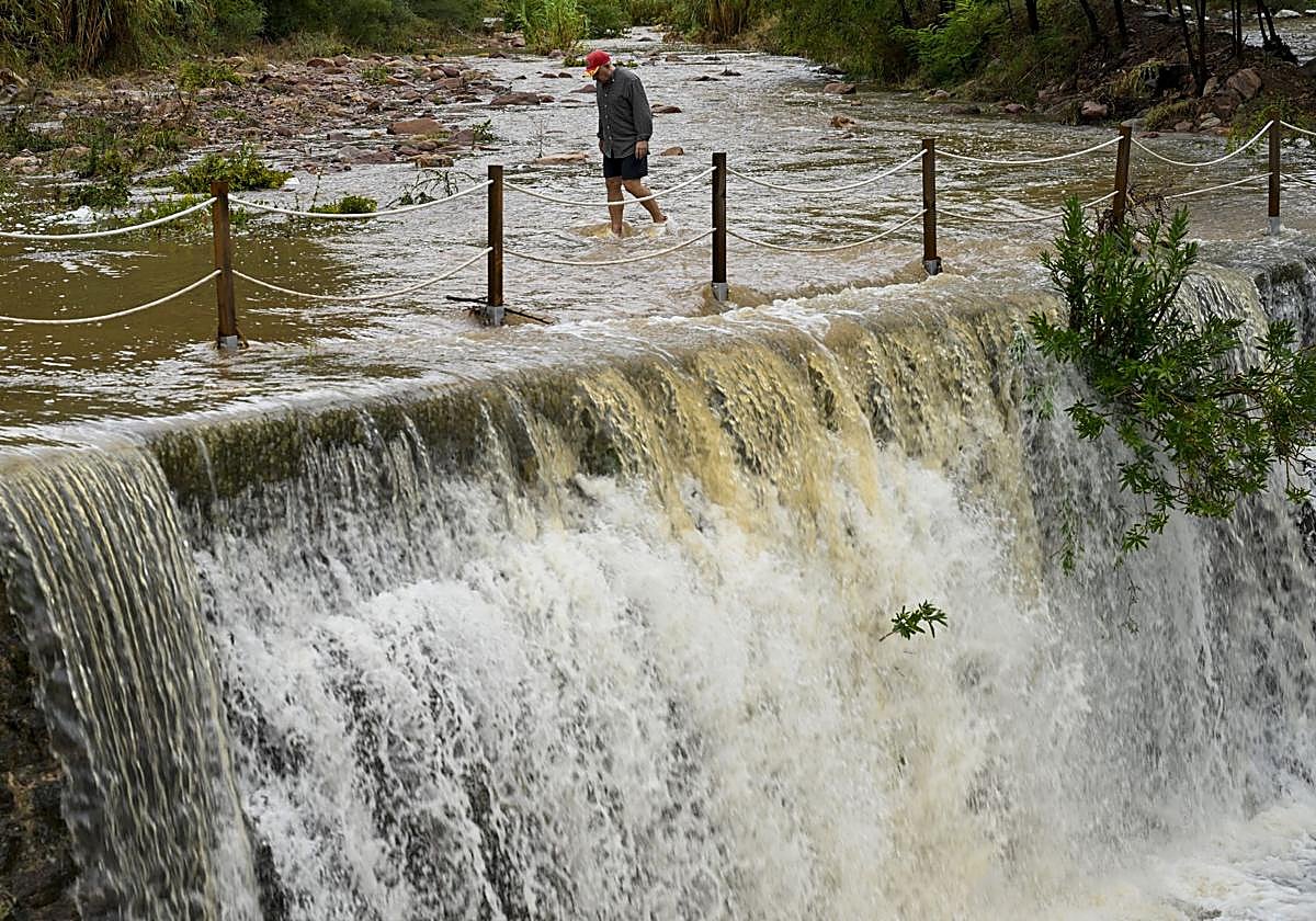 Un hombre cruza un badén inundable en Castellón.