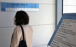 Una mujer observa el cartel que indica el acceso al Juzgado de Menores de Segovia.