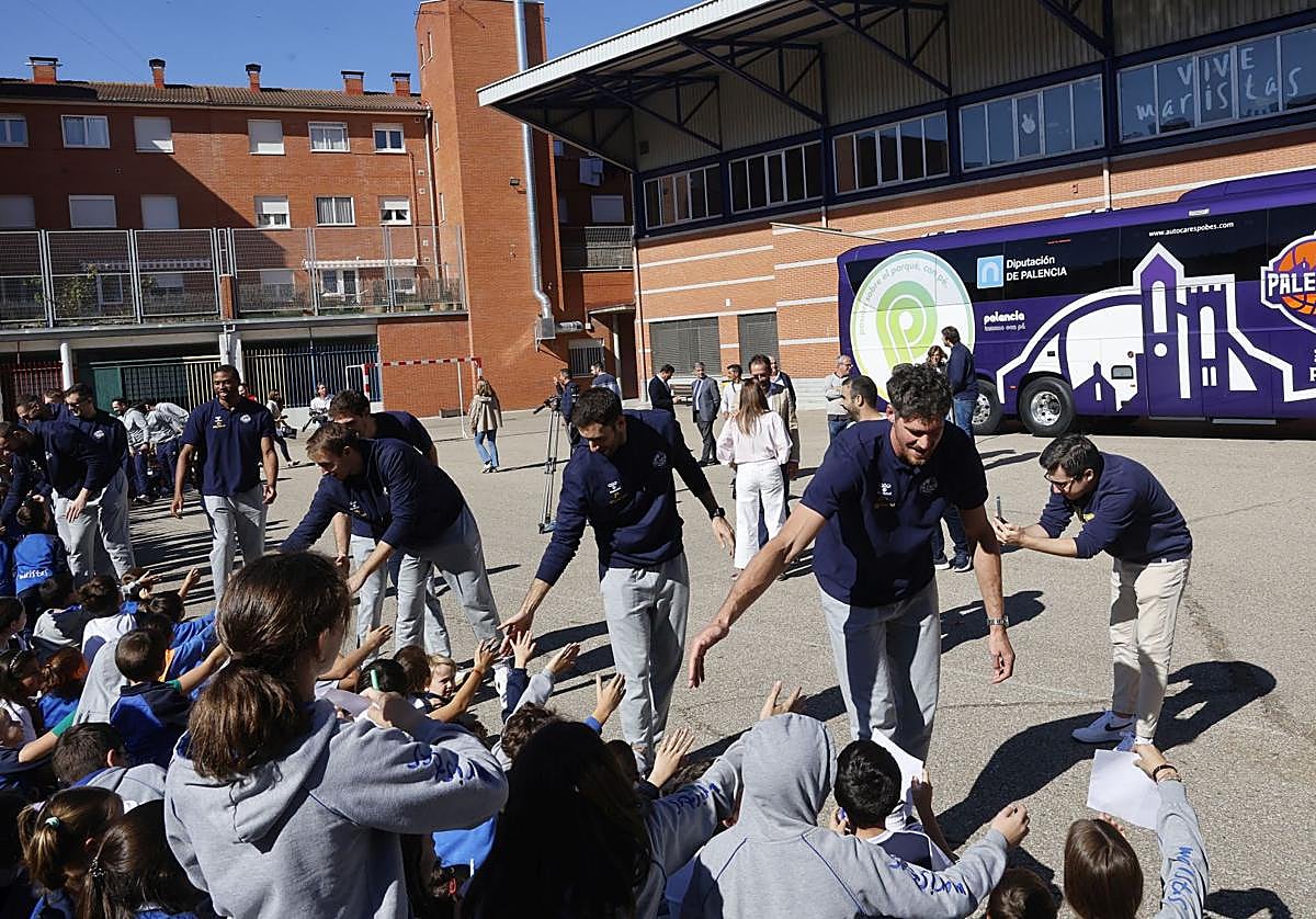 Los jugadores saludan a los alumnos de Maristas en el patio del colegio, con el autobús de fondo.