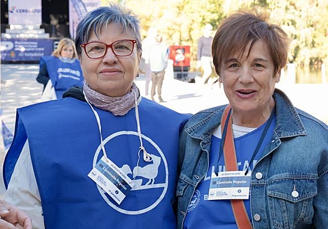 Las voluntarias Pepi Medina y Rosa Martínez junto a la mesa de las inscripciones en la marcha.