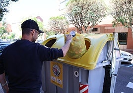 Un hombre tira una bolsa de basura en el contenedor amarillo.